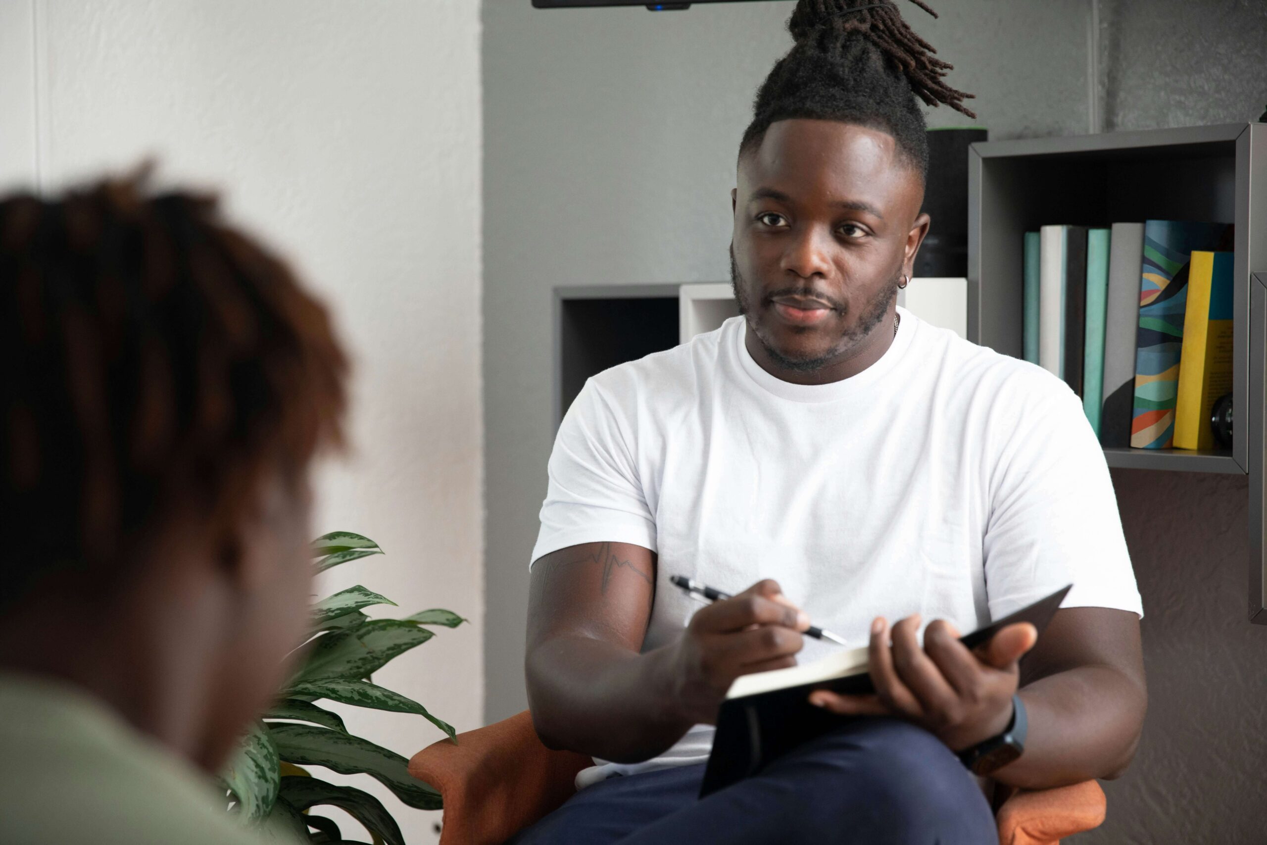 A young man sits in a therapists office.