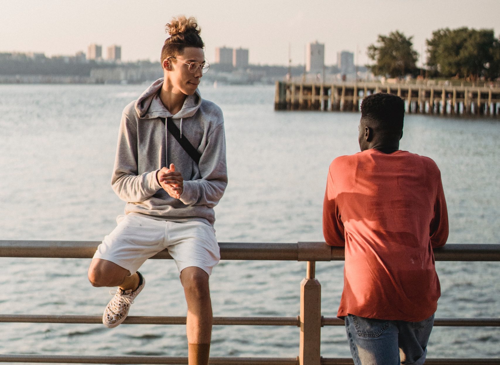 two young men talking outdoors overlooking water