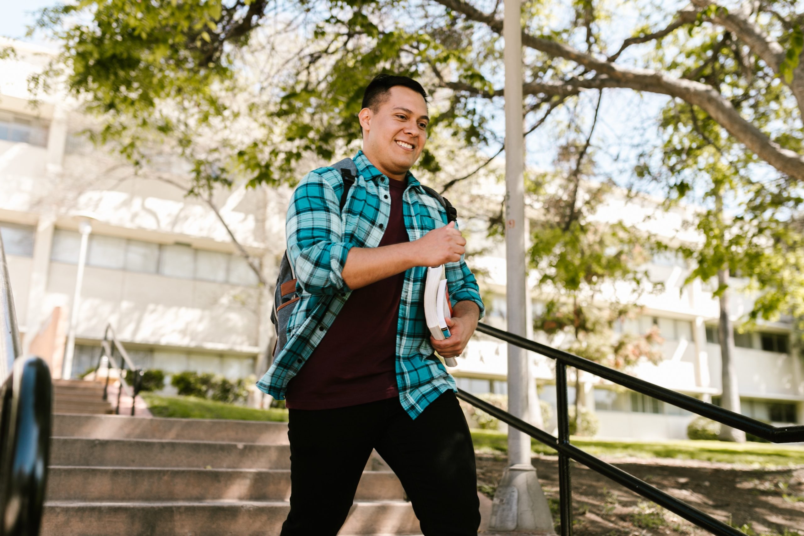 college student cheerfully walking down campus steps while holding books