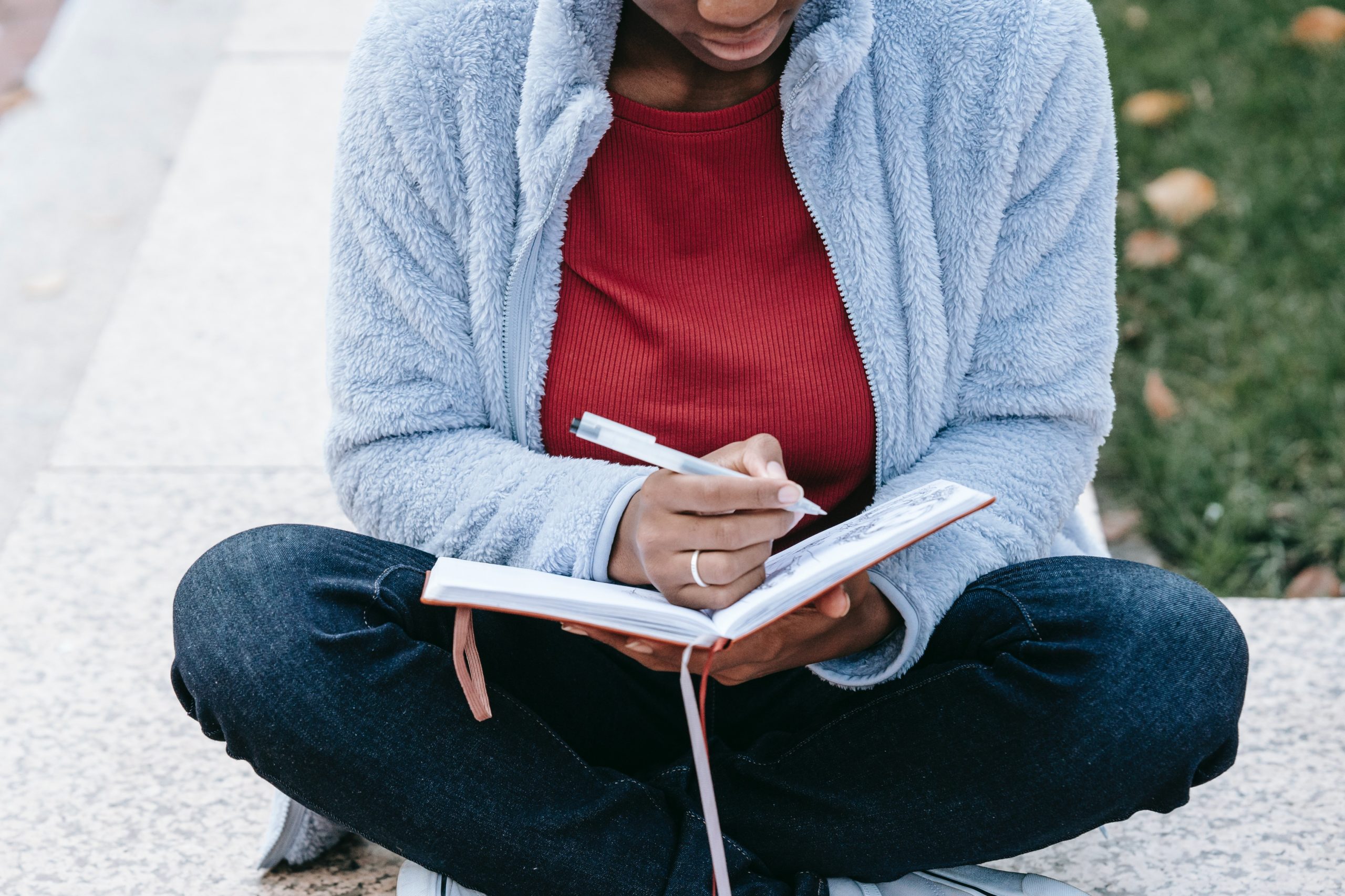 young person sitting outside writing in her journal