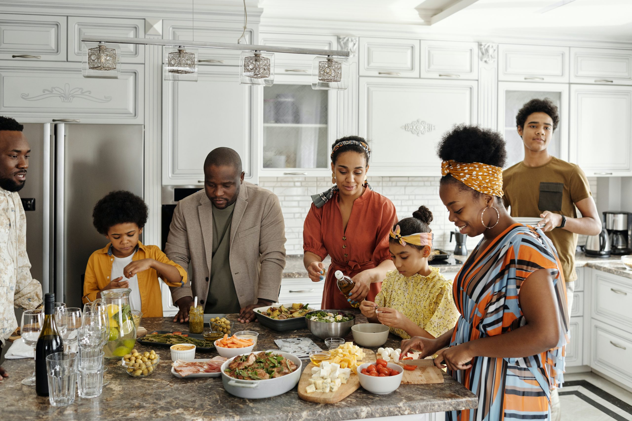 multi generational black family gathered together in kitchen with food dishes on the counter