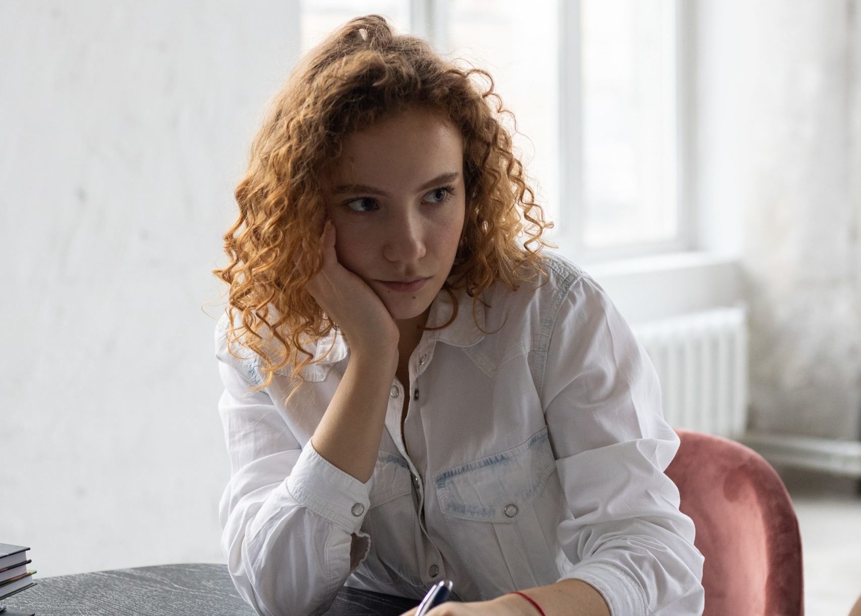 woman sitting in a chair at a table holding and deep in thought
