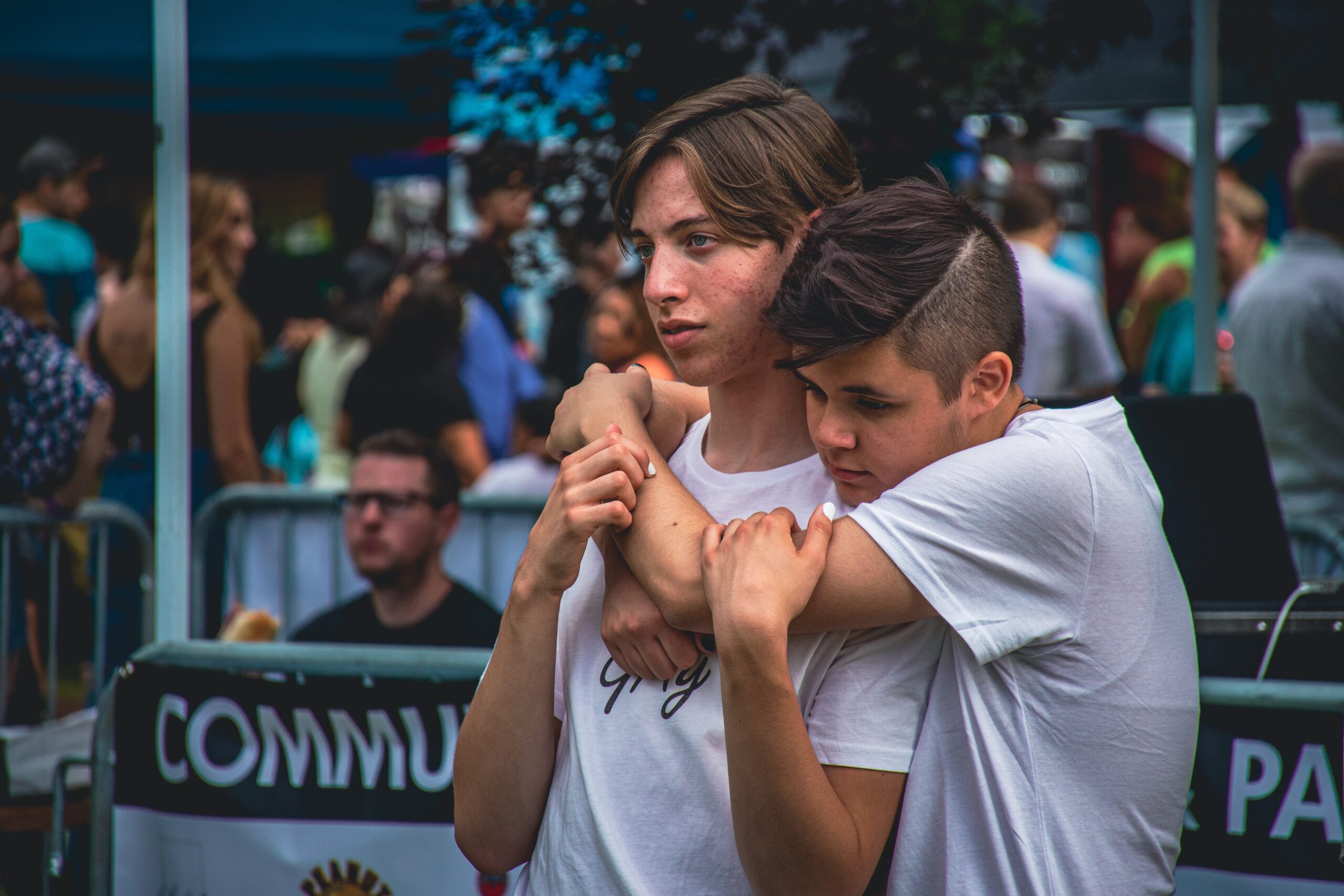 two young people standing outside comforting one another with one wrapping their arms over the shoulders of the other