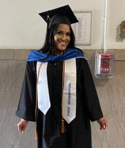 Brenda Leger, student oarent wearing black cap and gown, blue hood and honor ribbons