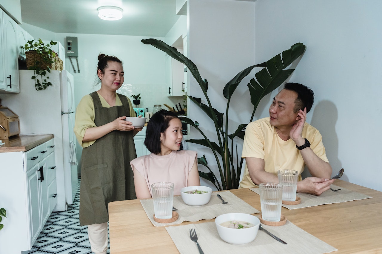 AAPI youth sitting at kitchen table talking to parents about mental health