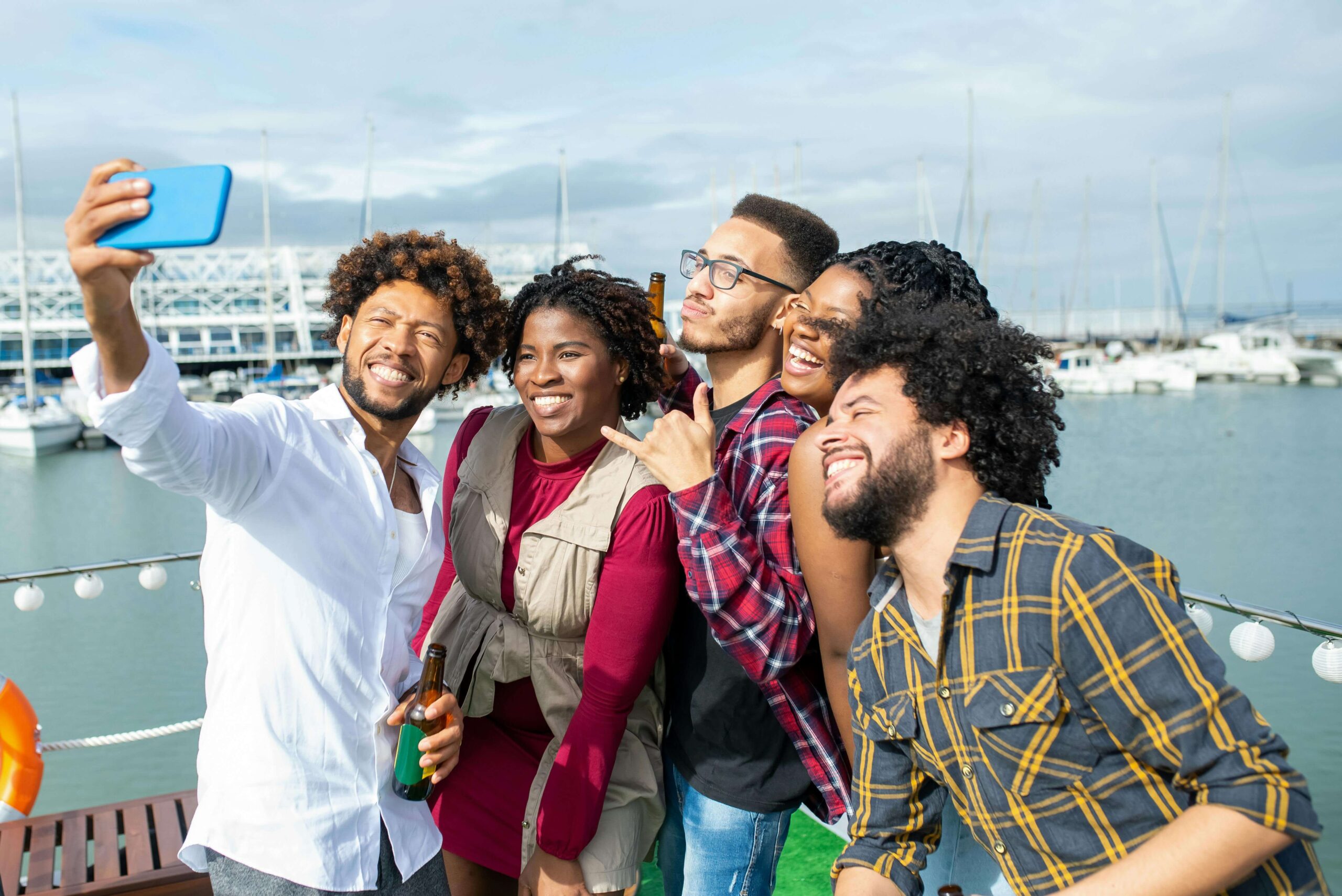 A group of teens standing on a doc smiling and taking a group photo.
