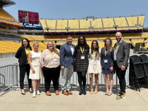 group of people standing outdoors smiling at a stadium