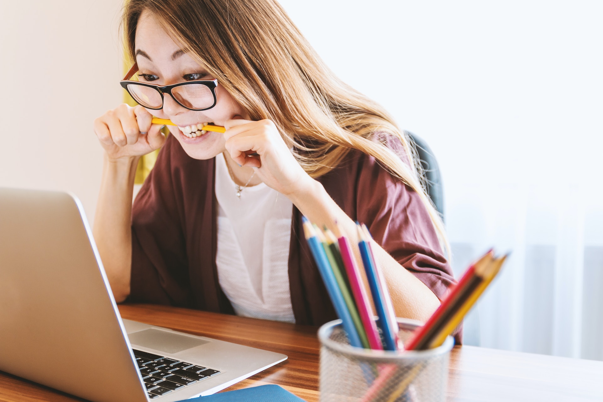 stressed looking student biting pencil while looking at laptop screen