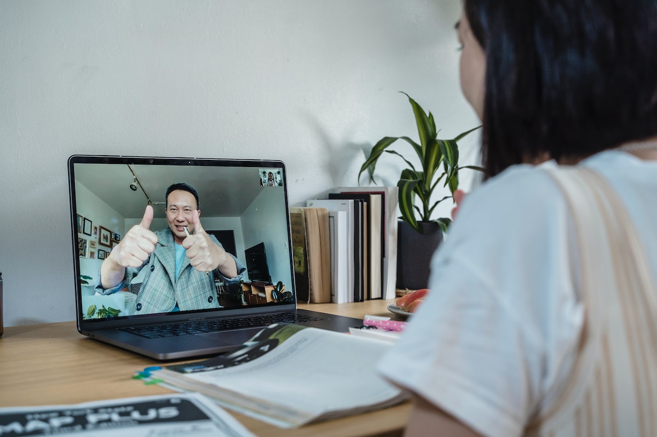 student sitting at table video chatting with dad via her computer