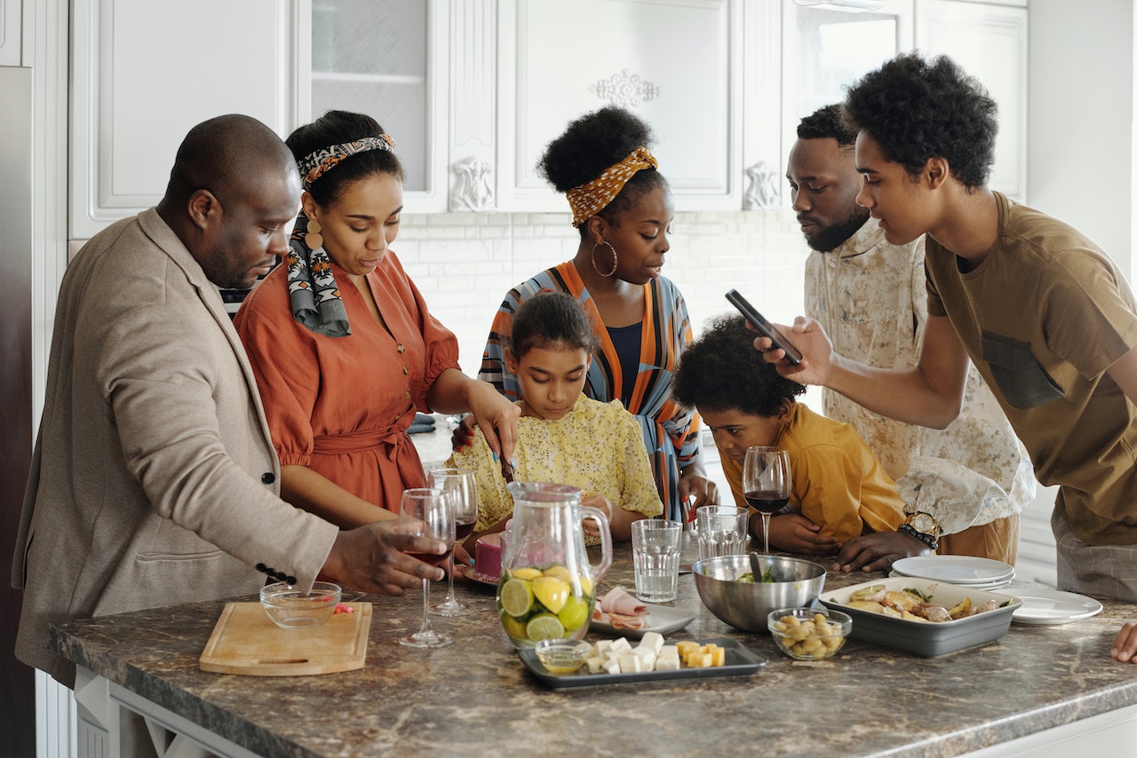family gathered at kitchen island as mom cuts a slice of cake