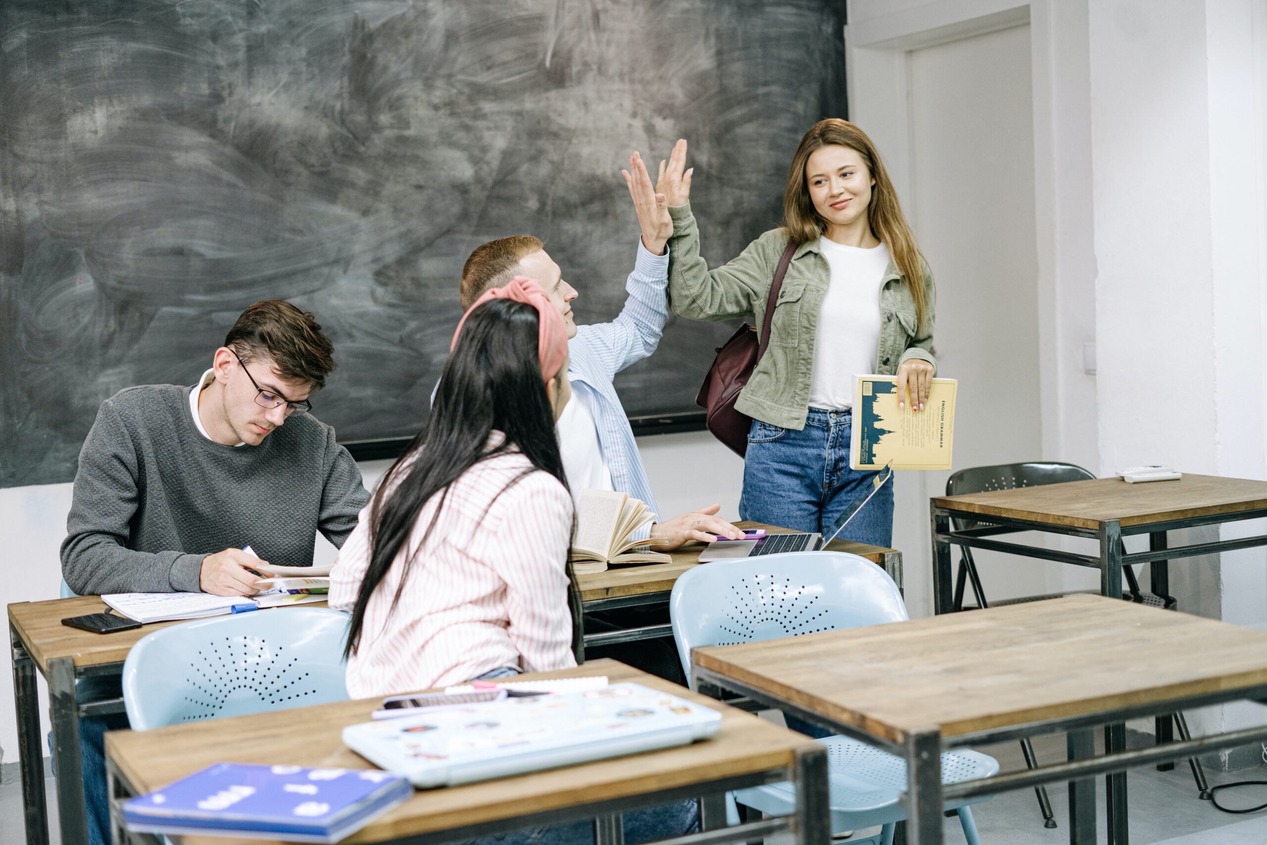 students in classroom talking with two students giving each other a high five