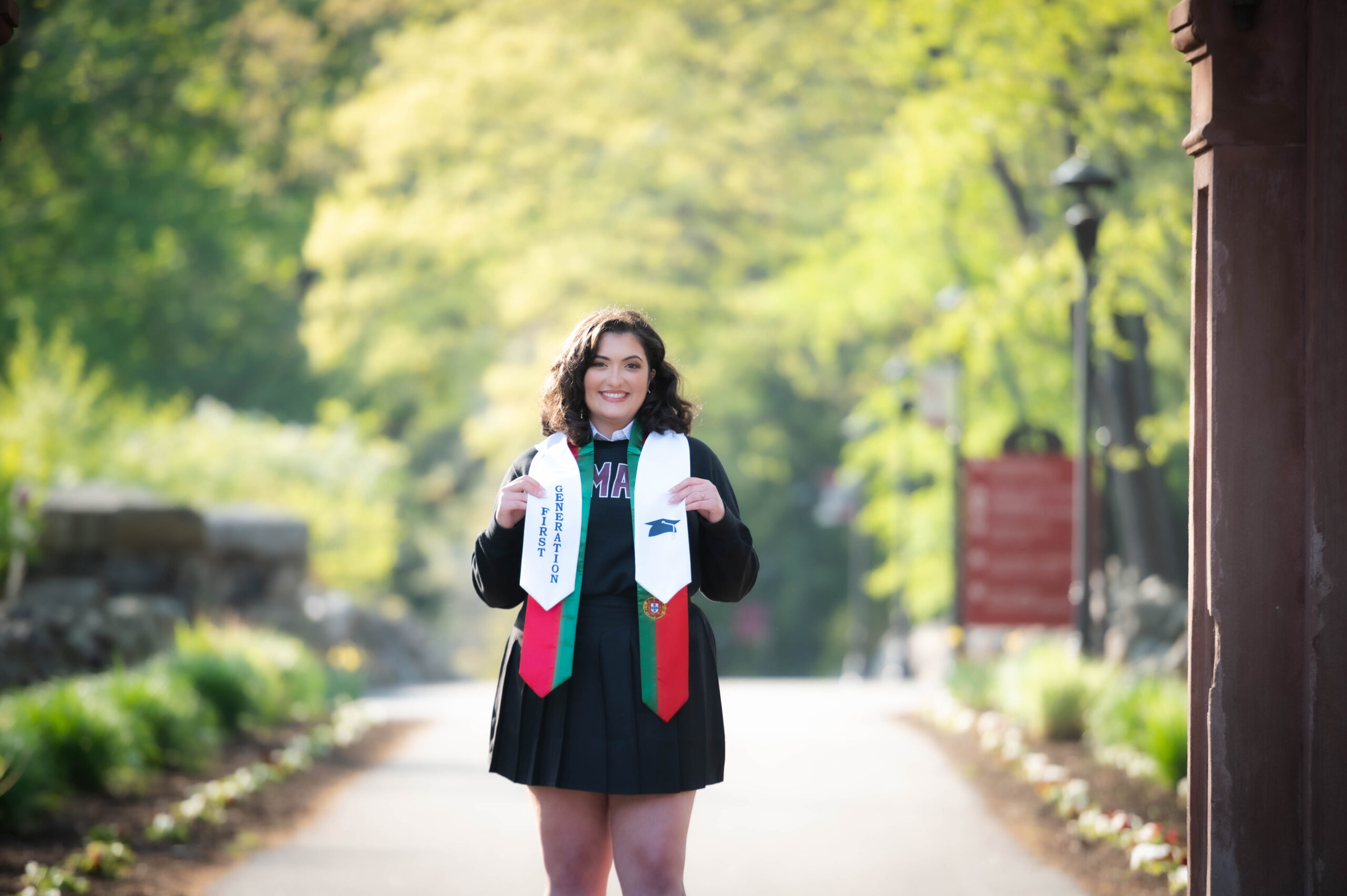 First-generation college student Gabriella Fonseca shows off her graduation stole while smiling.