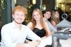 student JED florida gala attendees smiling while seated together a table