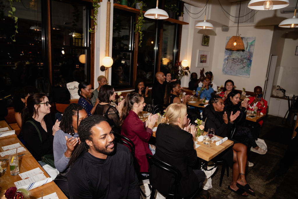 Attendees at the Lululemon Black Mat Yoga event sitting at their tables listening to remarks from Eric Mosley, a Lululemon Ambassador.