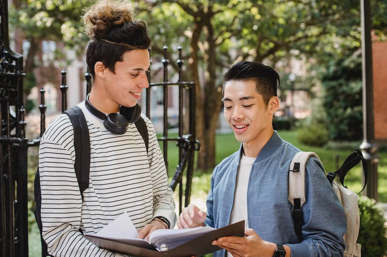 cheerful-multiethnic-students standing outside sharing-information-about-studies