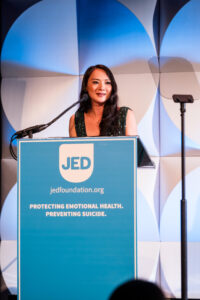 smiling woman standing a podium speaking into the microphone