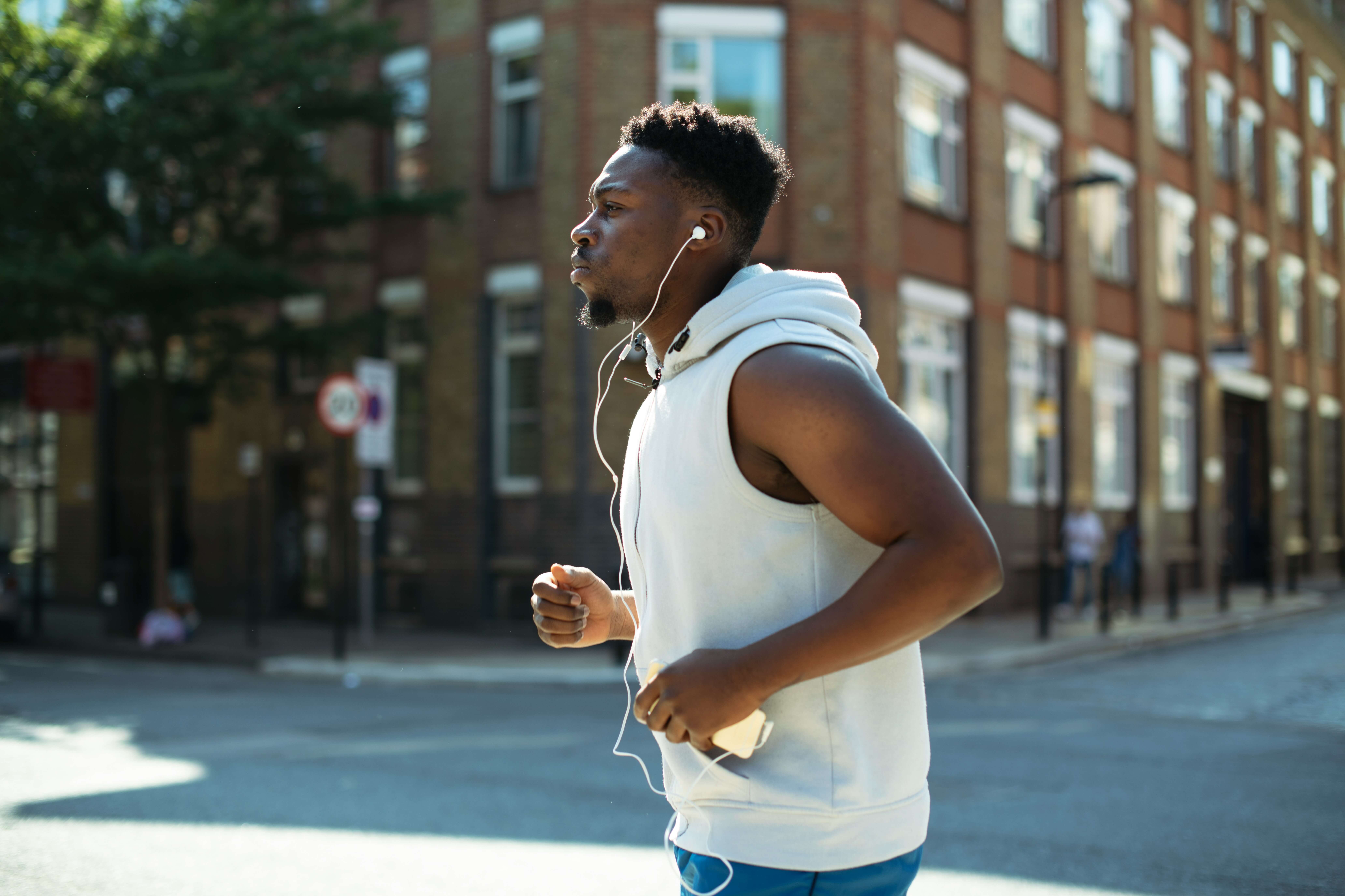 A young Black man out for a run while listening to music with earbuds.