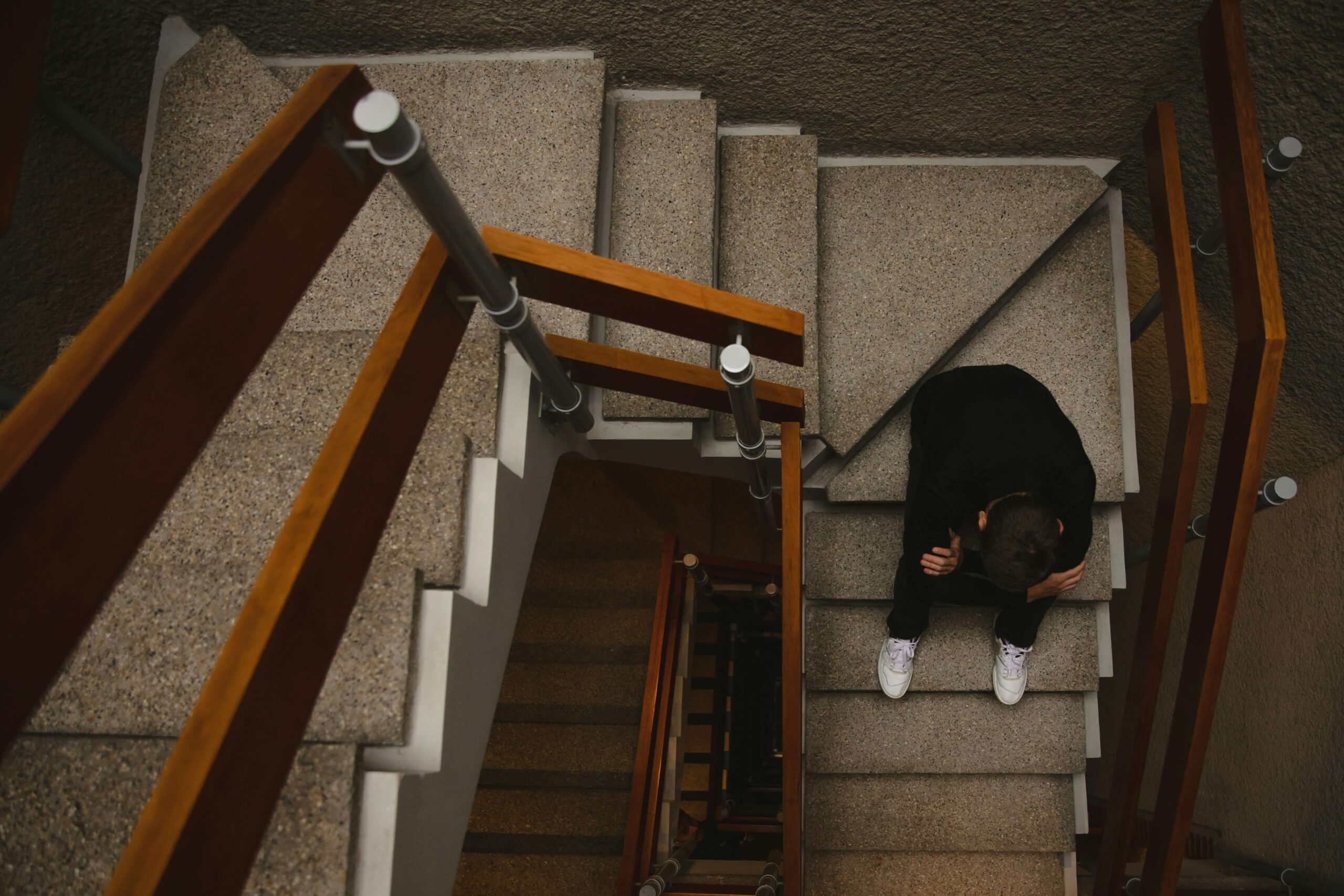 A person sitting on a staircase with their arms crossed and their head held low.