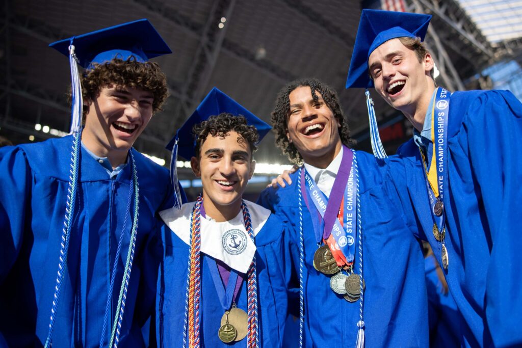 A group of graduating students from Minnetonka Public Schools in Minnesota wear blue caps and gowns a smile at their commencement ceremony.