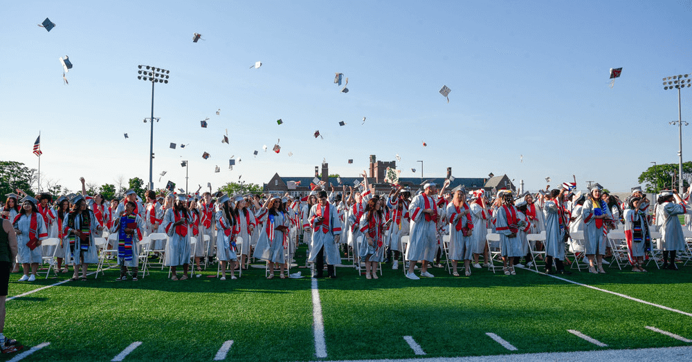 Students standing in a field throwing their graduation caps, celebrating their graduation from Vineland Public Schools in New Jersey.