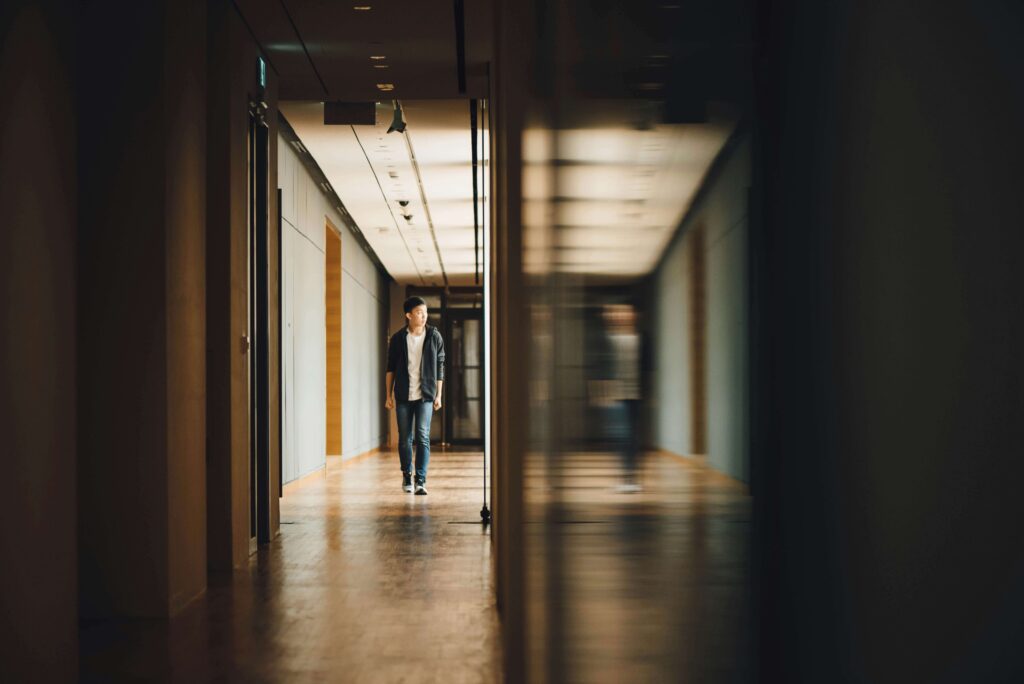 A student walks down a school hallway and sees their blurry reflection to their side.