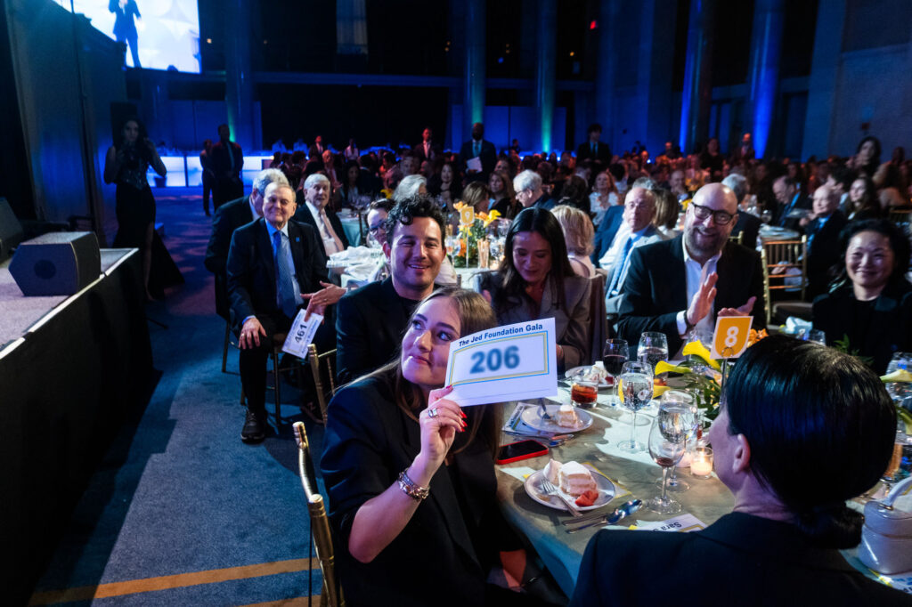 Photo from inside The Jed Foundation's 2025 Gala, including attendees smiling, clapping, and enjoying the event.