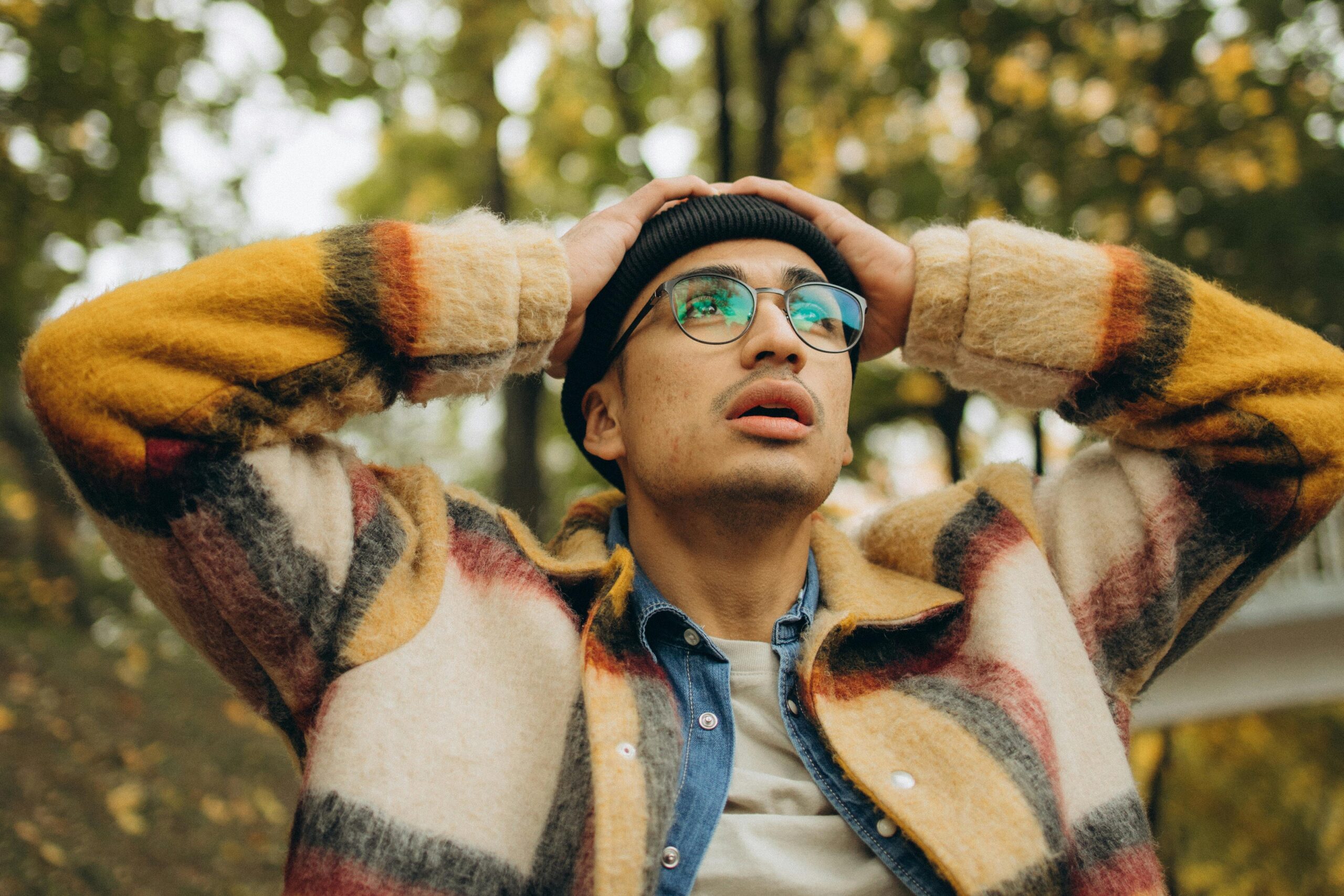 Person with glasses touching his hand, looking up with an uncertain and confused look.