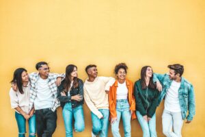 group of smiling students lined up against of yellow wall