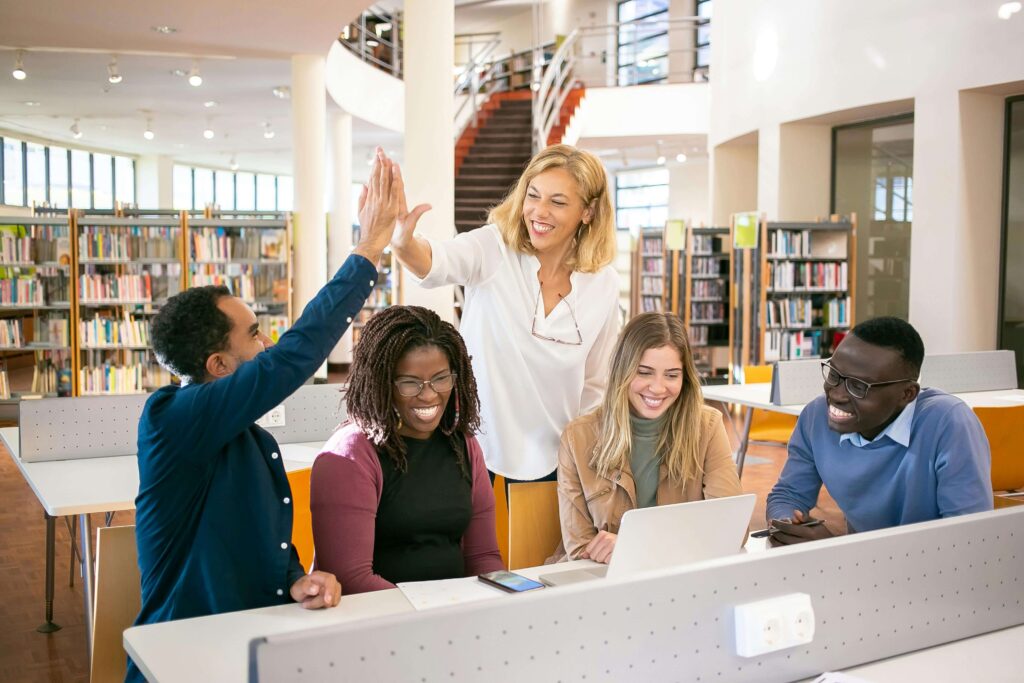 Teacher high-fiving students in the library